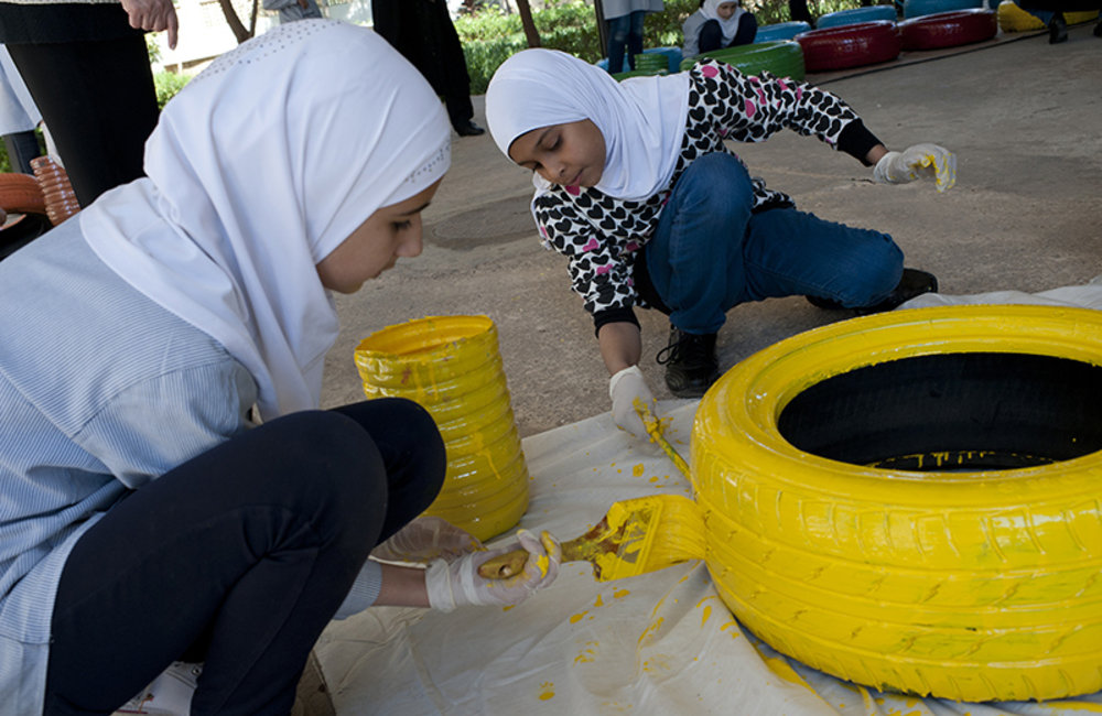 Two girls painting a recycled tire a Tyre public school.