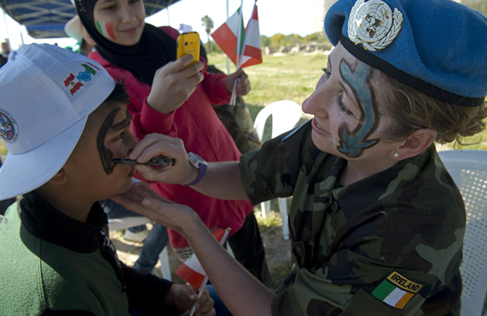 Irish soldier painting the face of a participant.