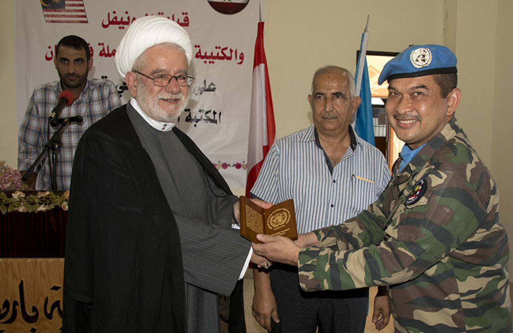 Lt.Col Zunaidi Hassan, the deputy commander of the Malaysian Battalion, presents a plaque of appreciation to Sheikh Hussein Darwish,the Imam of Barish.