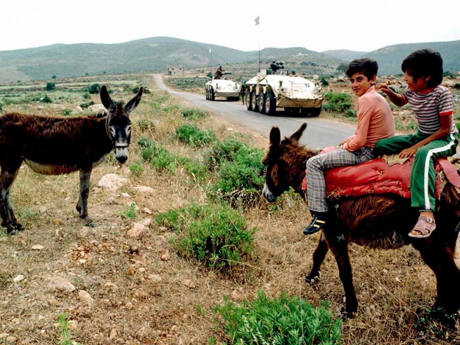 Boys riding donkey in front of UN patrol