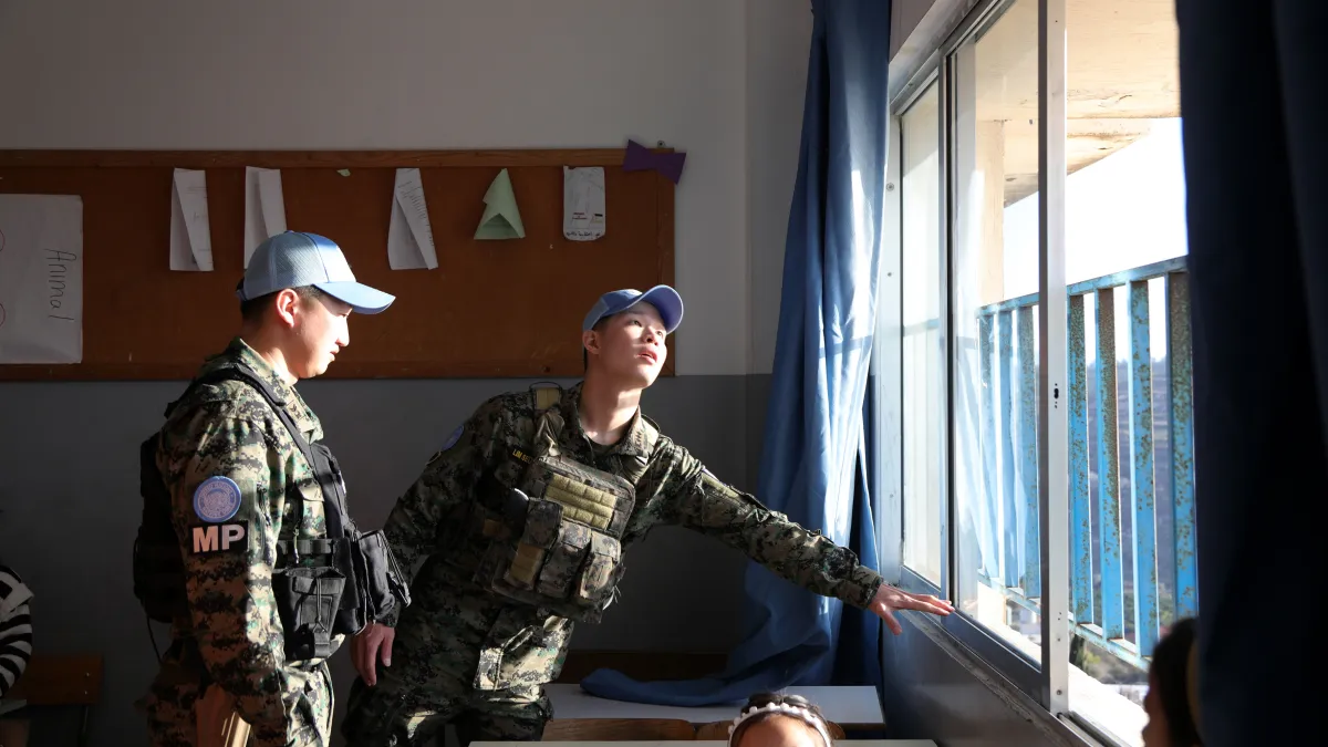 Two peacekeepers checking the installation of a window