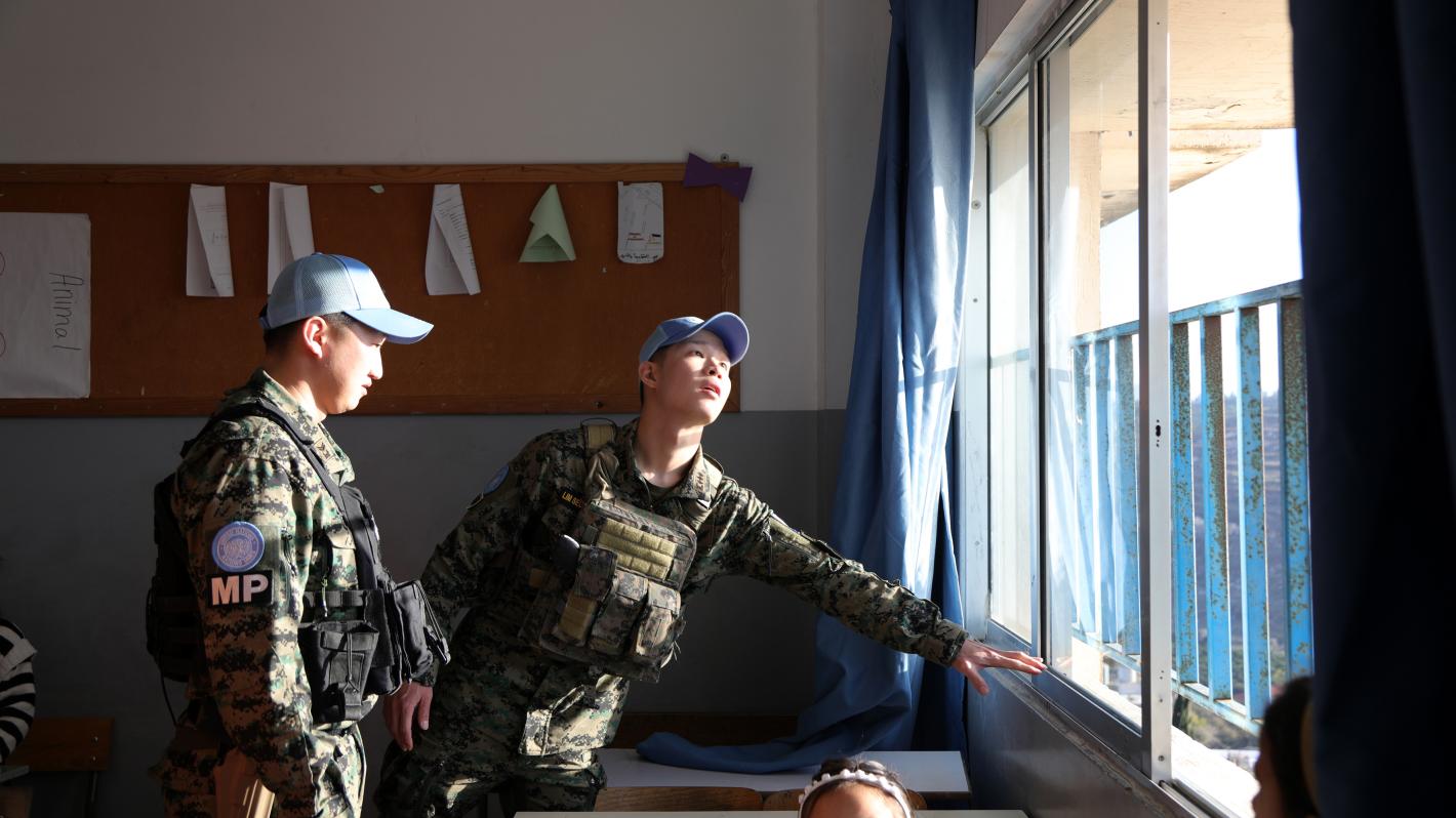 Two peacekeepers checking the installation of a window