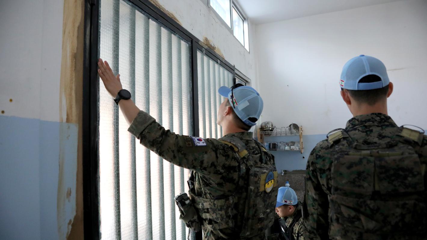 A peacekeeper installing a window in a school