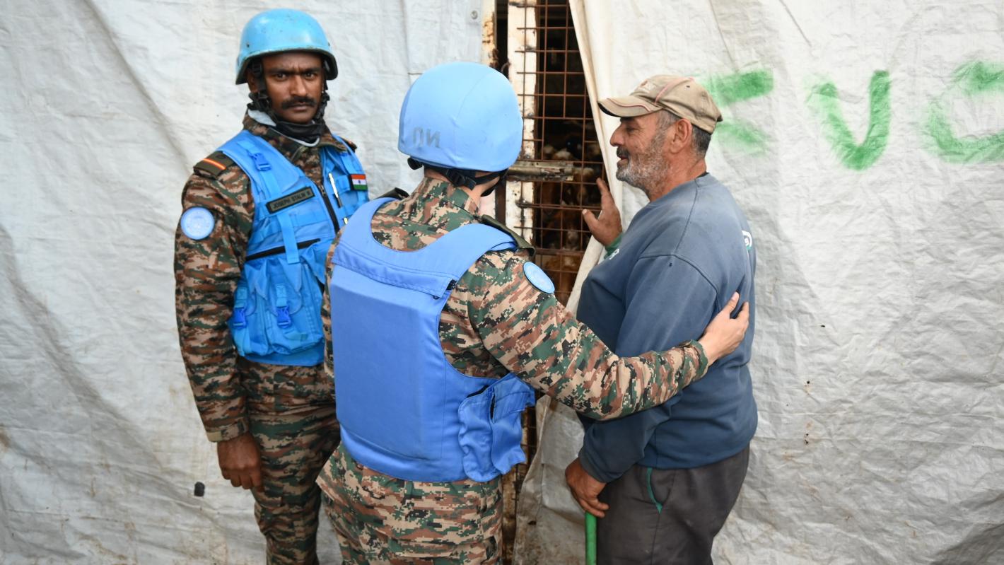 A peacekeeper showing a civilian behind a curtain into a cage with livestock inside
