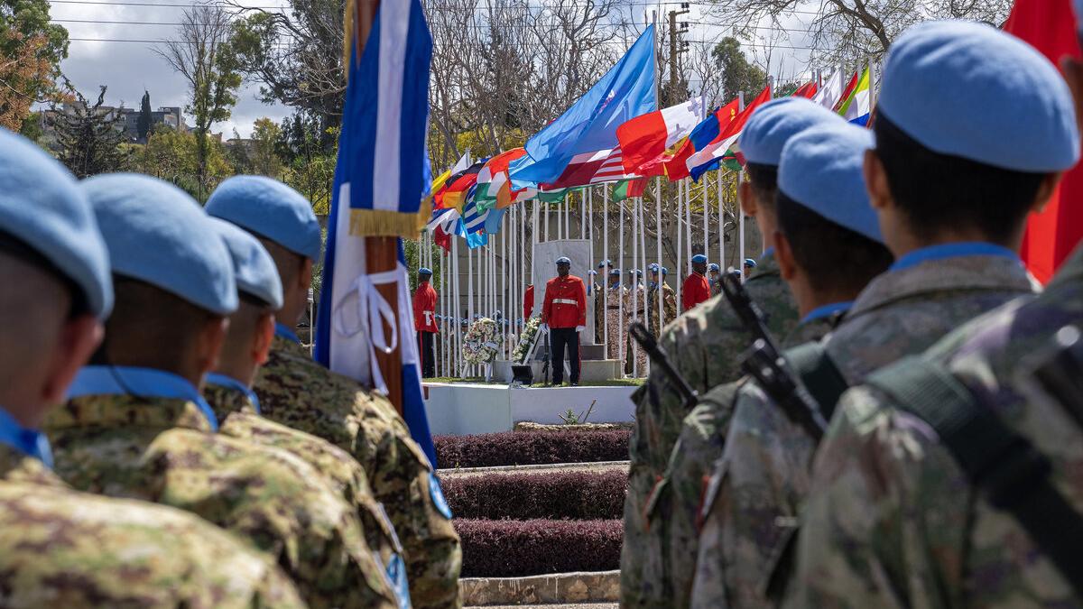 Peacekeepers stand facing a stage.