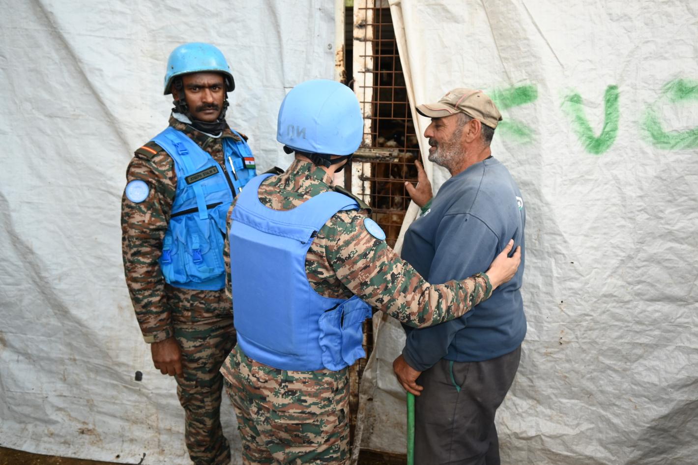 A peacekeeper showing a civilian behind a curtain into a cage with livestock inside
