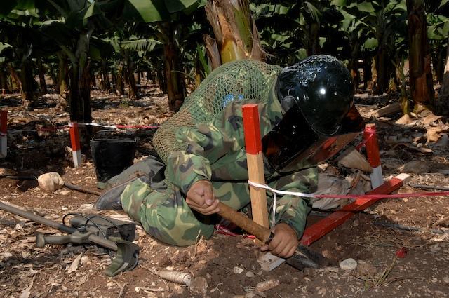 UNIFIL's Chinese deminer at work in south Lebanon. A deminer digging in the ground wearing protective equipment.